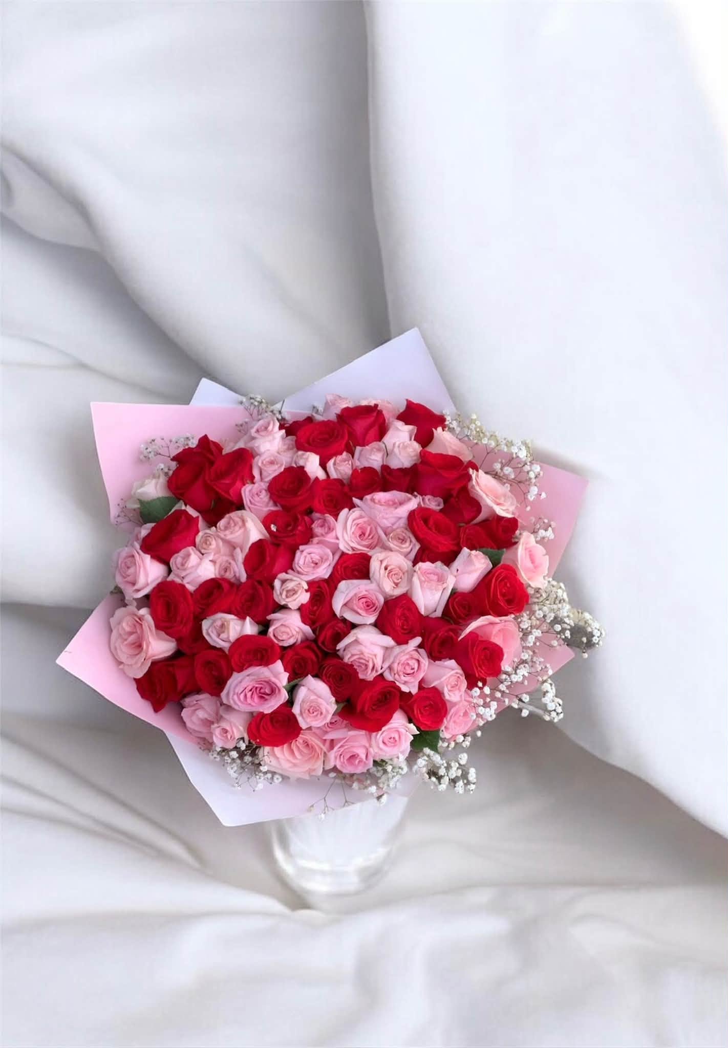 Arreglo de rosas rojas y rosas preparado por Flores Para Ti, con envoltura rosa y flores de nube