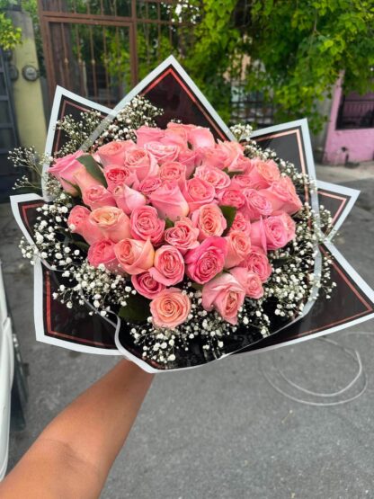 Ramo del taller con rosas en tono rosa, nube blanca y envoltura negra; referencia de diseño.