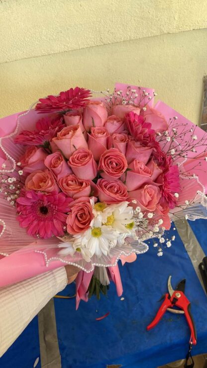 Ramo del taller con rosas rosas, gerberas fucsias, margaritas blancas, nube y envoltura rosa; referencia de diseño.