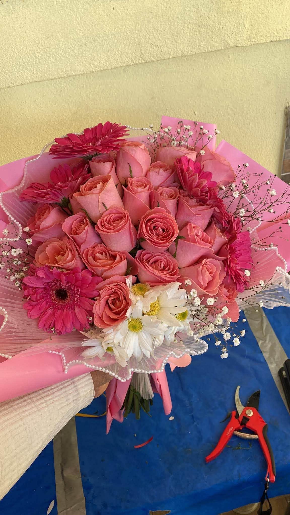 Ramo del taller con rosas rosas, gerberas fucsias, margaritas blancas, nube y envoltura rosa; referencia de diseño.